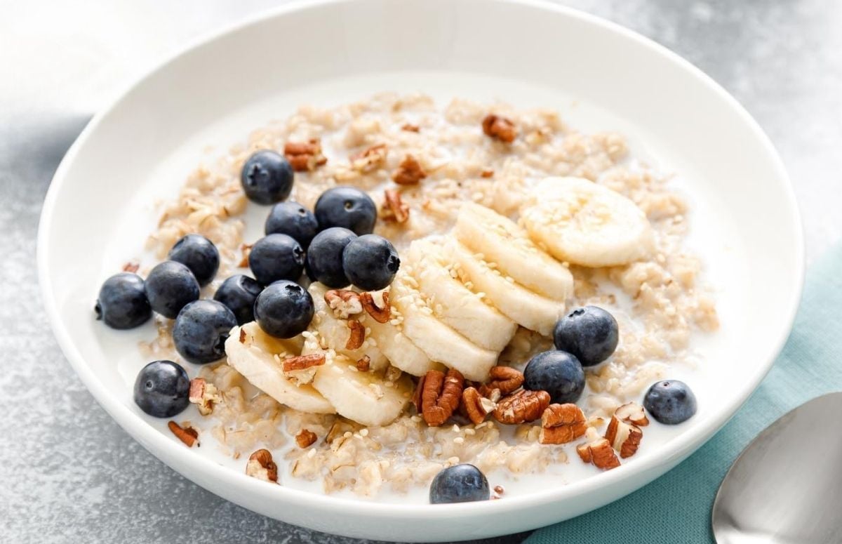 bowl of oatmeal topped with blueberries, banana slices and chopped nuts