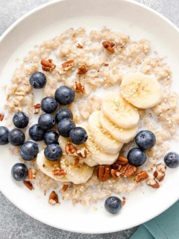 bowl of oatmeal topped with blueberries, banana slices and chopped nuts
