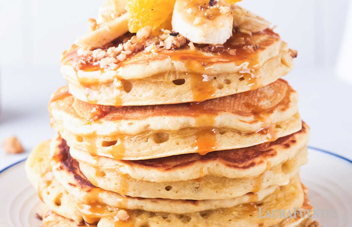 fluffy pancakes topped with caramel sauce nuts and fruit