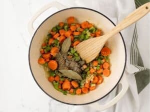 celery, carrots, and onions mixed with seasonings and bay leaves in a pot