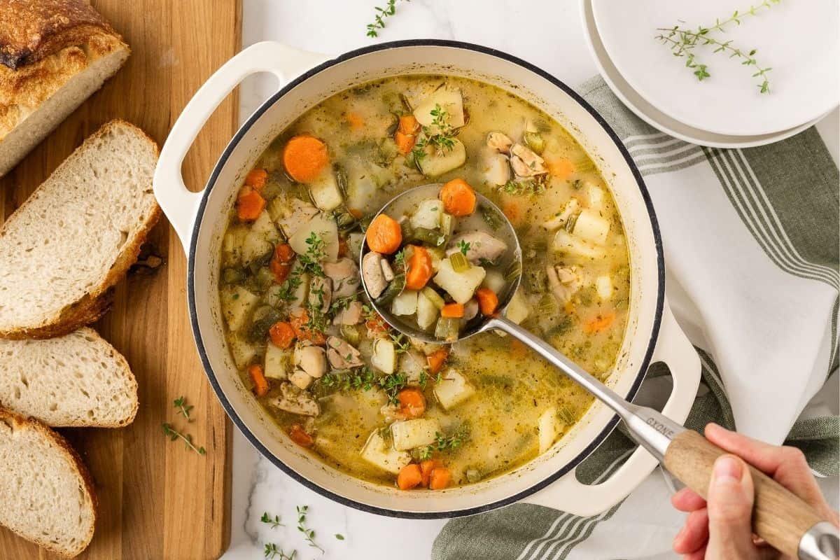 woman's hand stirring a pot of chicken potato stew 