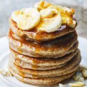 small stack of pancakes topped with fruit and nuts