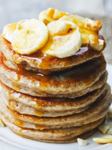 small stack of pancakes with banana and nuts