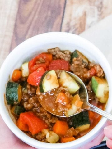 overhead view of a bowl of paleo chili and a hand holding a spoon