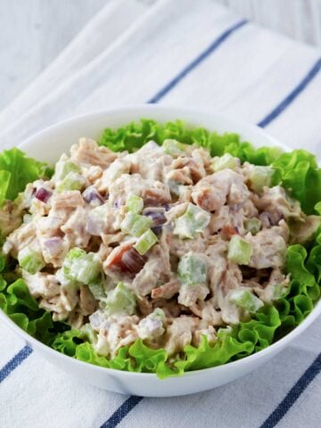 a bowl with a bed of lettuce and chicken salad on top