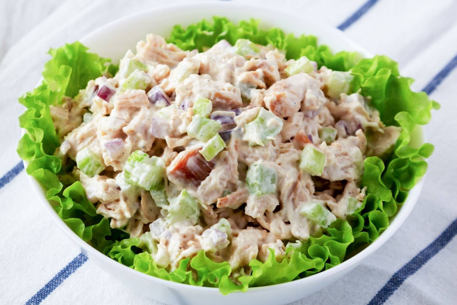 a bowl with chunky chicken salad on a bed of green