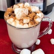 a mug of hot cocoa topped with marshmallows and more around it