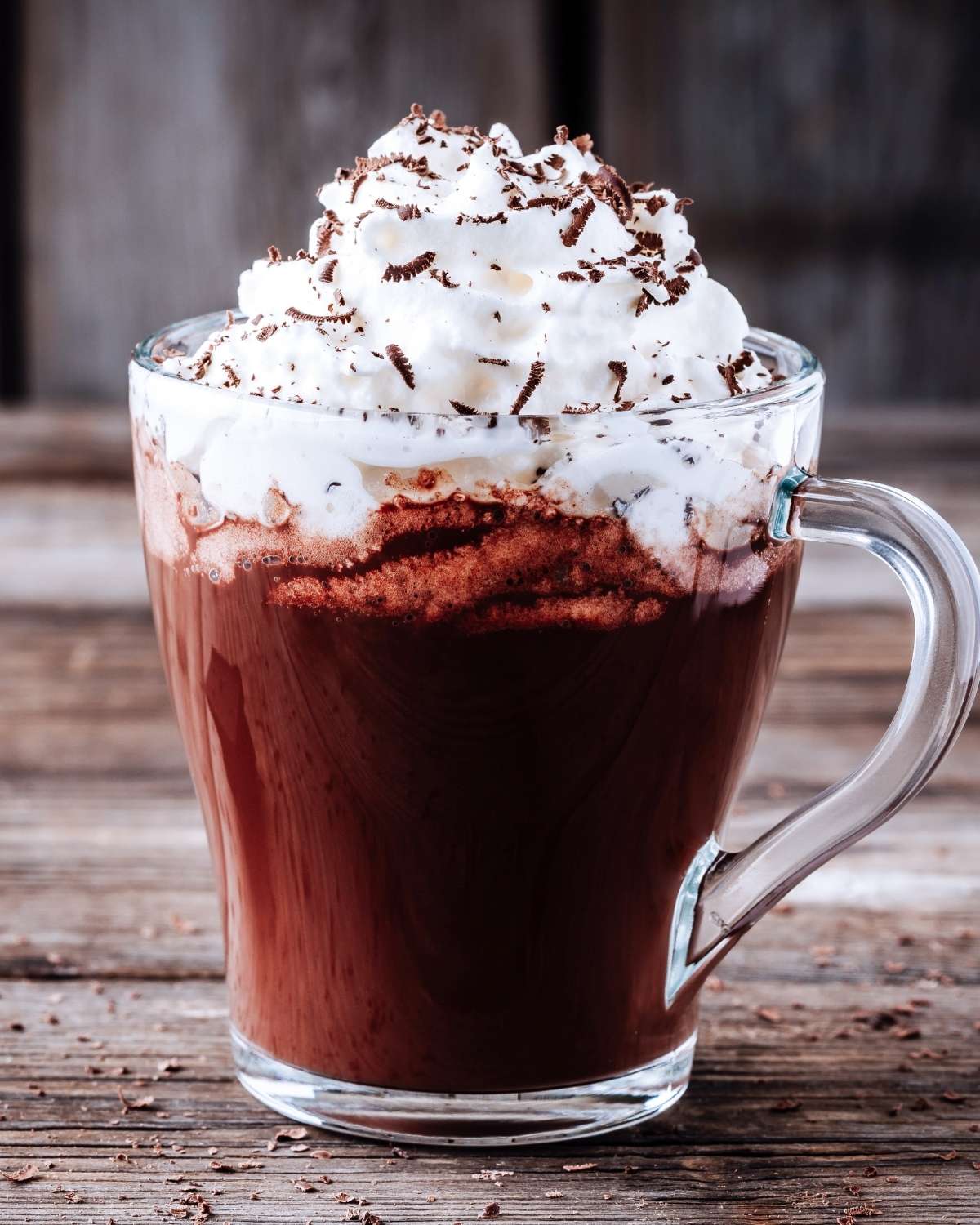a glass mug with hot chocolate topped with whipped cream