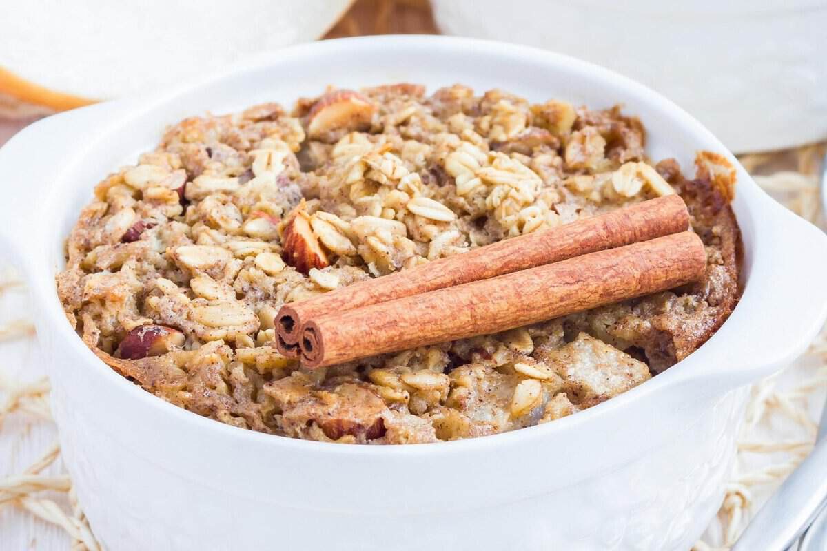 a bowl of pear baked oatmeal with two cinnamon sticks on top