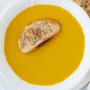 a bowl with butternut squash soup and a slice of toast on top