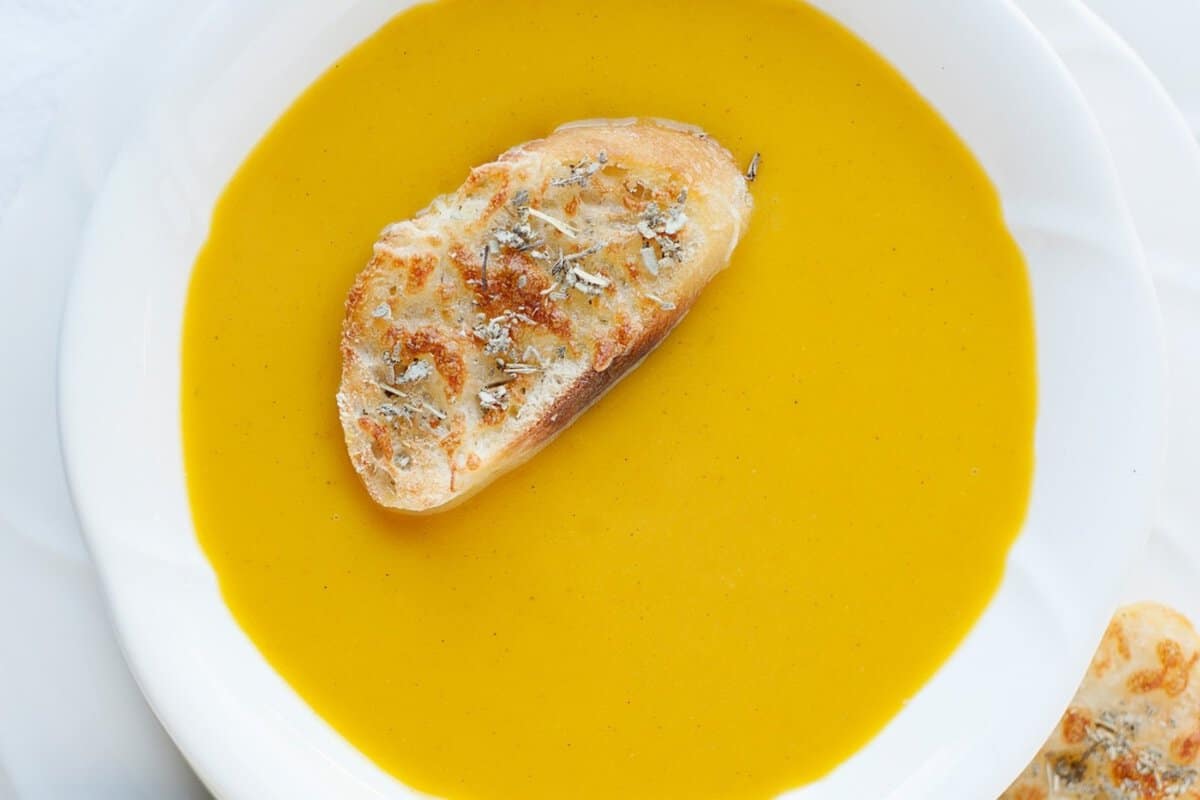 a bowl with butternut squash soup and a slice of toast on top