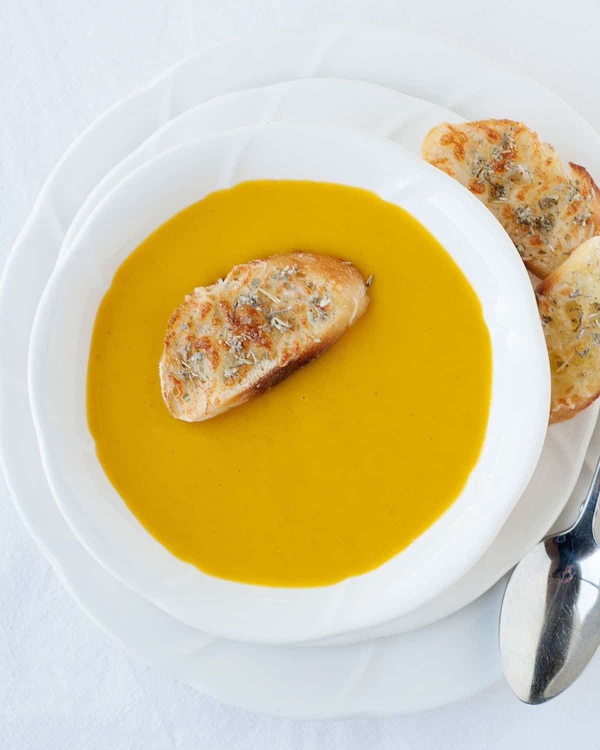 a bowl with butternut squash soup and a slice of toast on top