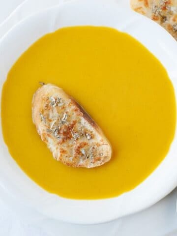 a bowl with butternut squash soup and a slice of toast on top