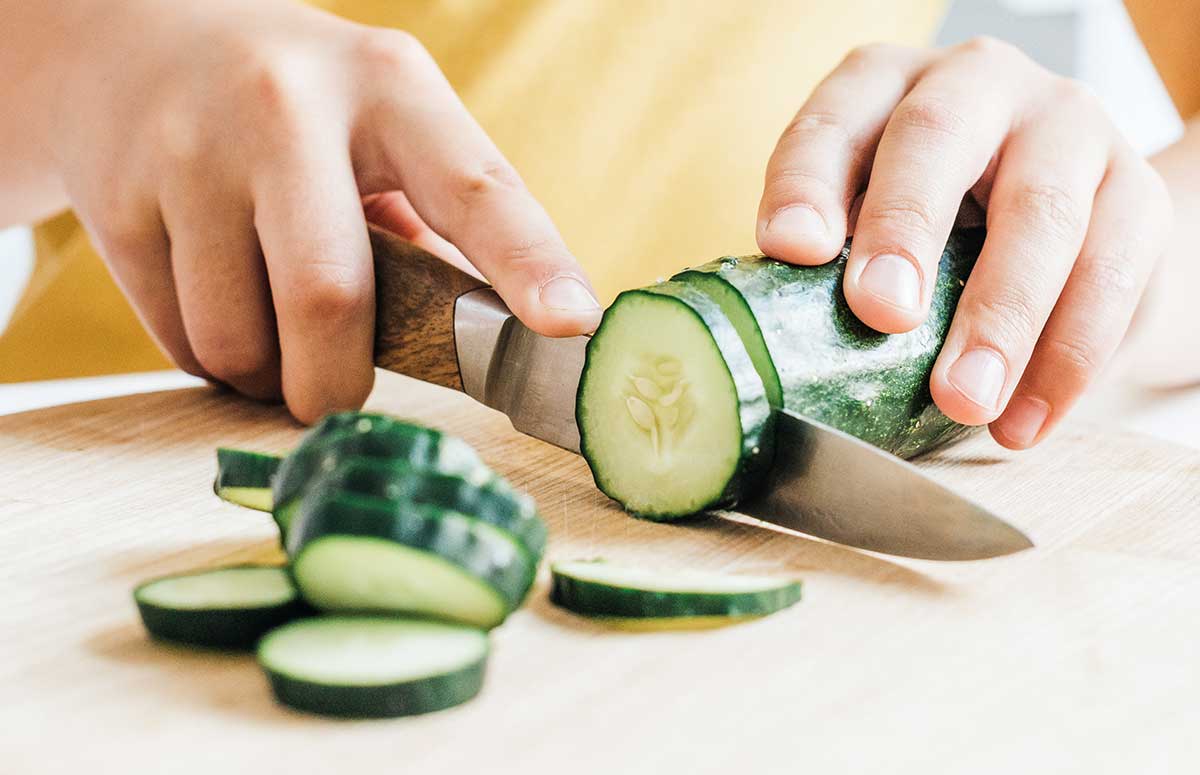 cutting a cucumber into slices on a cutting board
