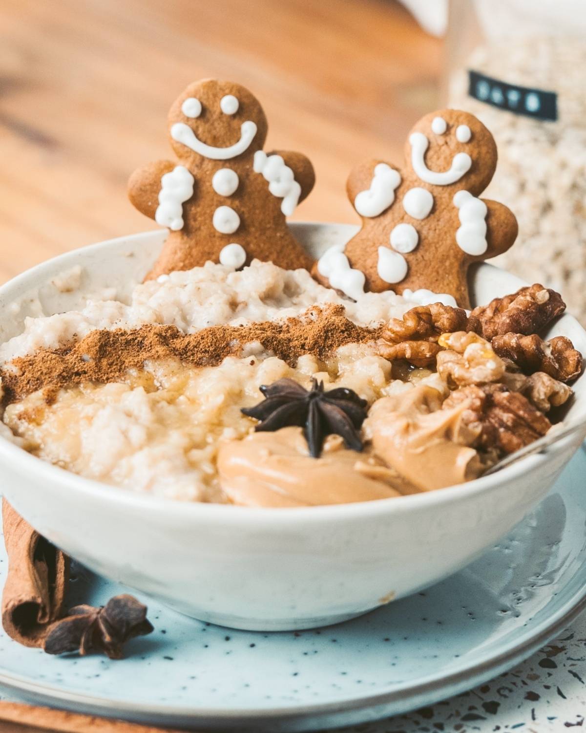 gingerbread oatmeal topped with two gingerbread men, nuts, cinnamon, and peanut butter
