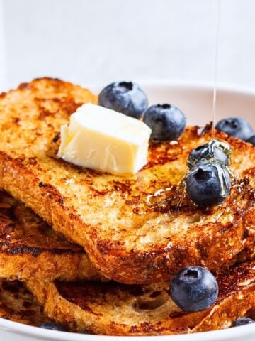 a stack of french toast topped with butter and blueberries