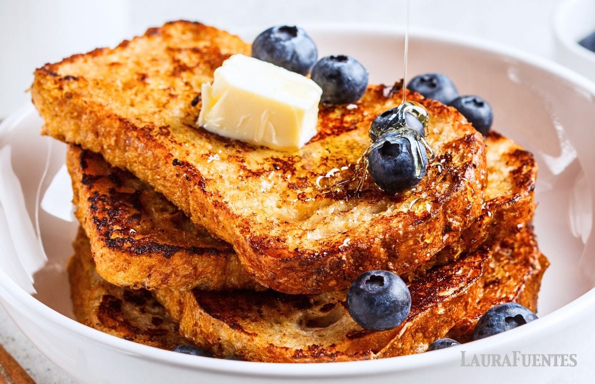 a stack of french toast topped with butter and blueberries
