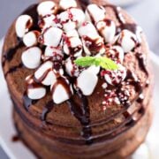 stack of chocolate pancakes topped with mini marshmallows and chocolate syrup