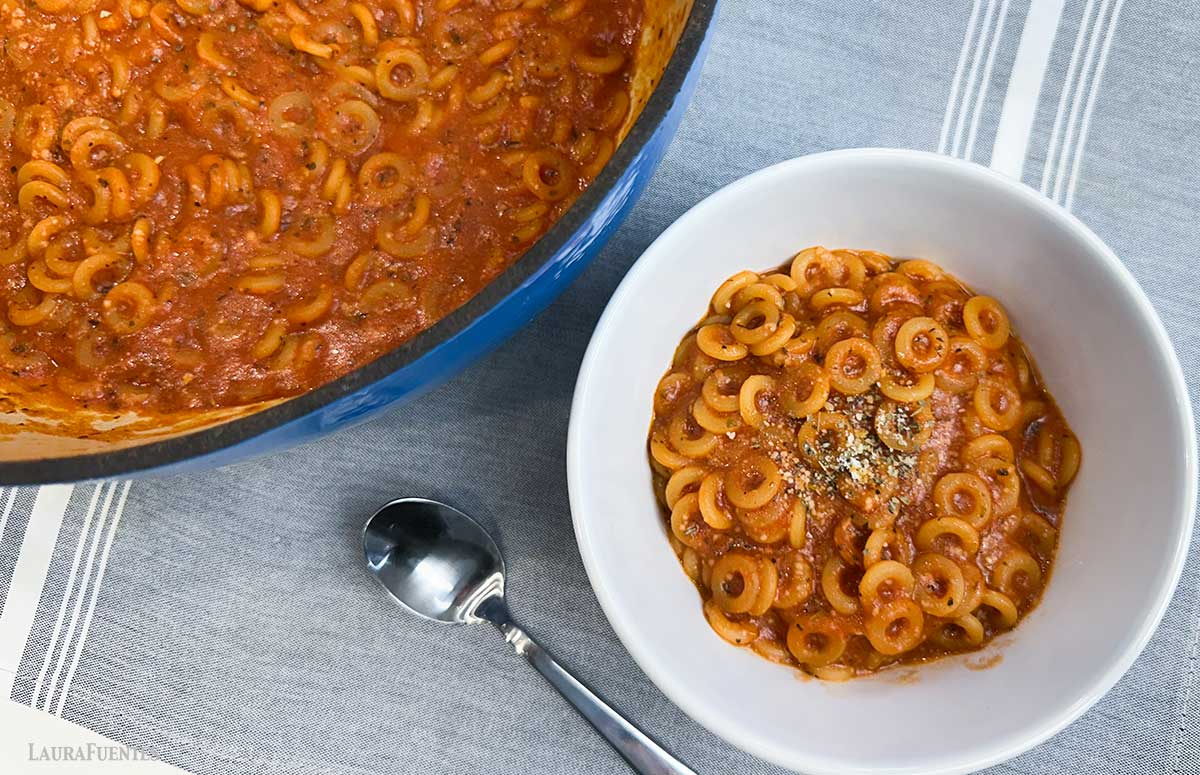 bowl of homemade spaghettios next to a large dish of spaghettios