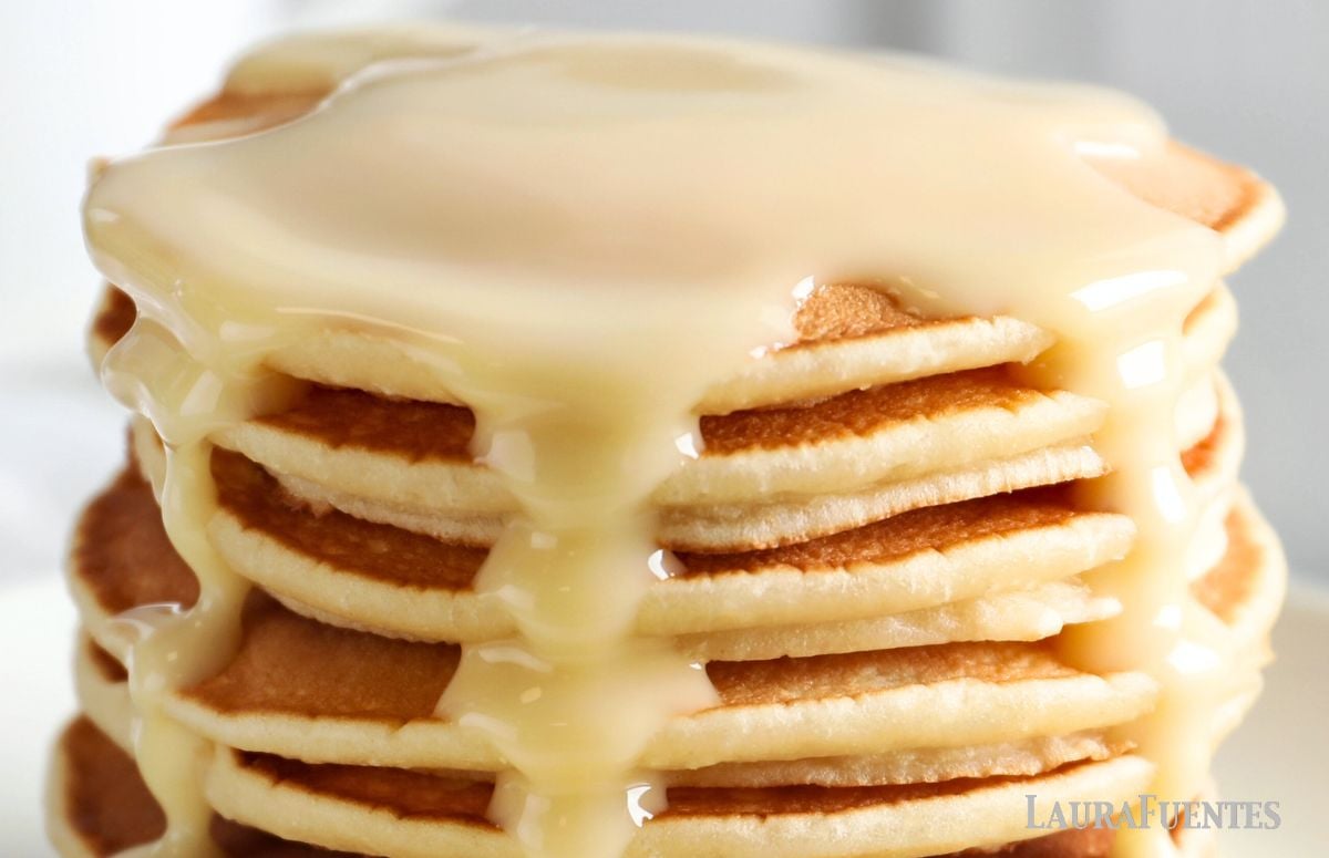 stack of fluffy pancakes topped with condensed milk