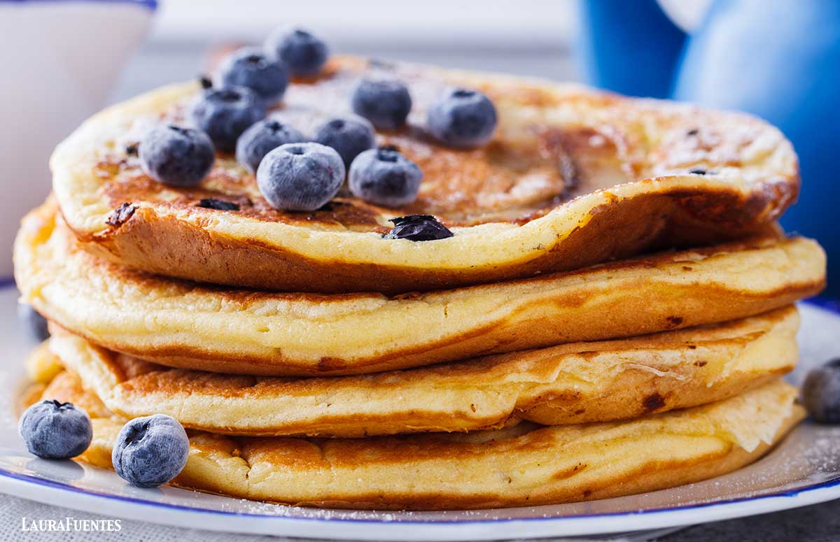 side view of four pancakes stacked and topped with blueberries