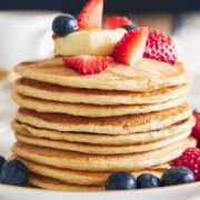 stack of oatmeal cottage cheese pancakes topped with mixed berries and sliced bananas