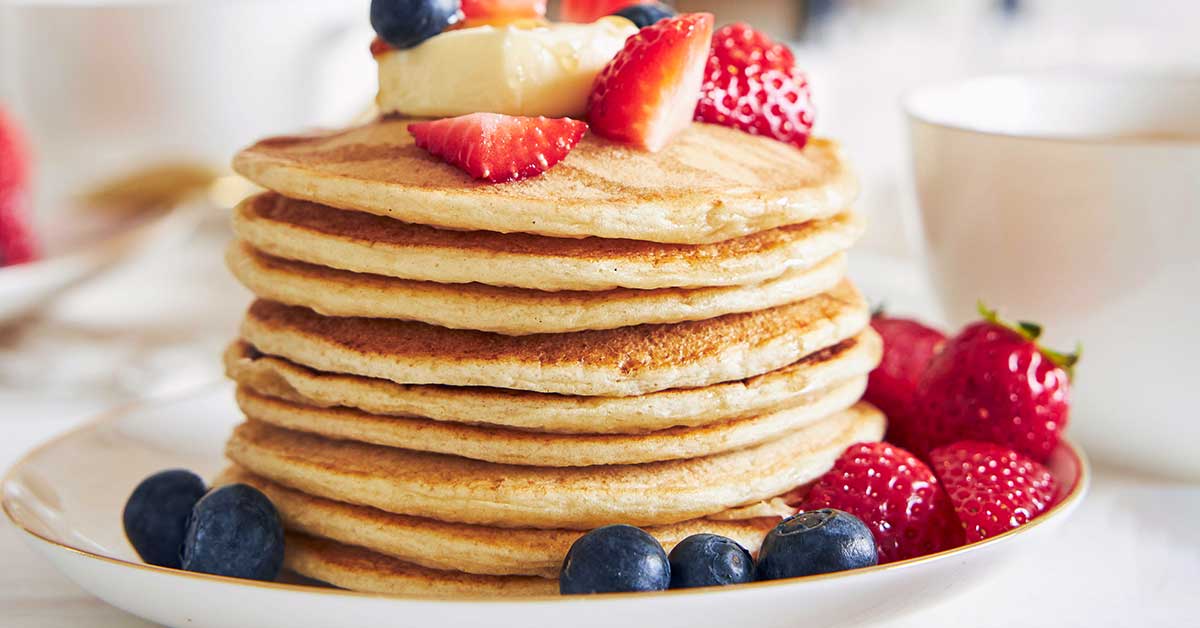 large stack of oatmeal cottage cheese pancakes topped and surrounded by fruit