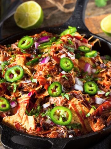pulled pork taco sin a skillet topped with sliced jalapenos