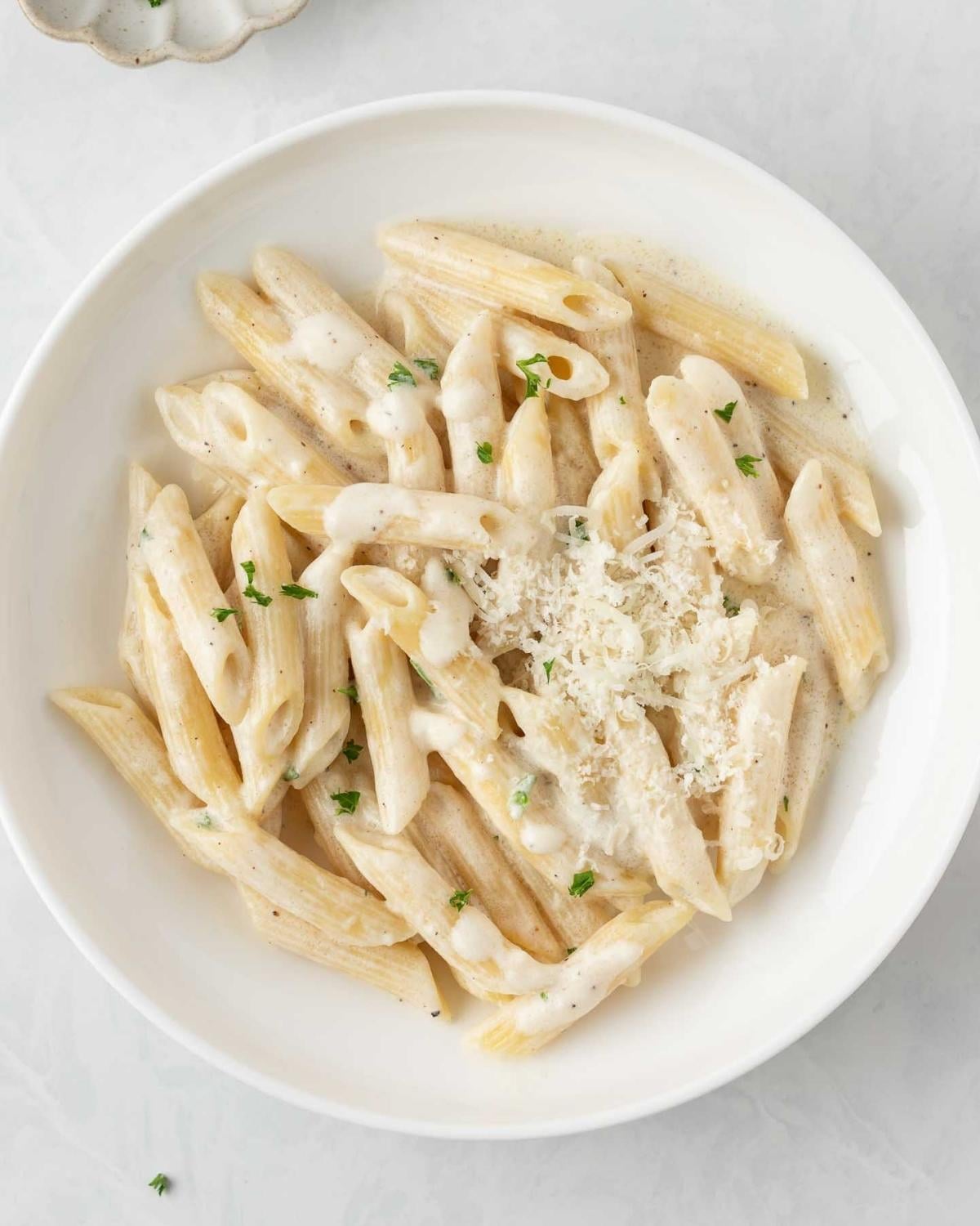 top view of pasta penne with Alfredo sauce in a white dish