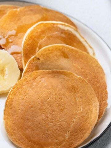 pancakes on a plate topped with blueberries and banana slices