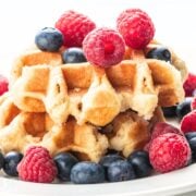 two waffles on a plate topped with raspberries and blueberries