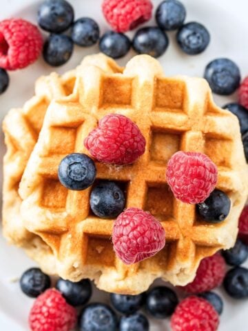 overhead view of waffles topped with syrup raspberries and blueberries