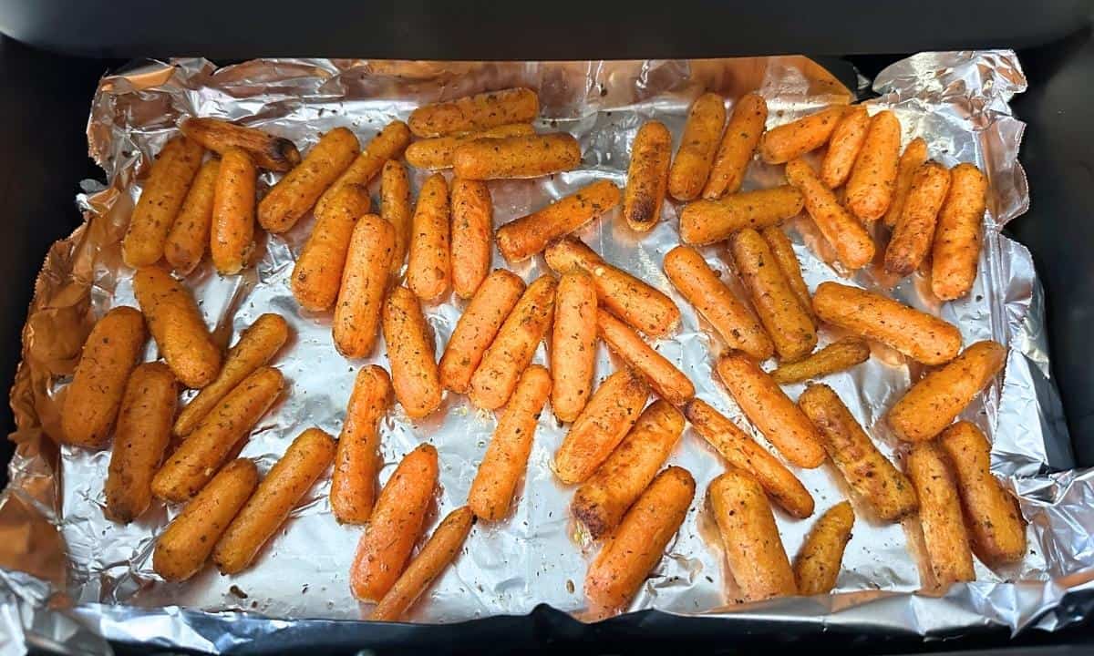 cooked baby carrots in a lined air fryer basket