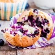 A blueberry muffin made with cottage cheese split open in half showing the light and airy texture with lots of juicy blueberries baked right in