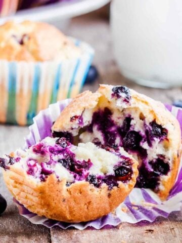 A blueberry muffin made with cottage cheese split open in half showing the light and airy texture with lots of juicy blueberries baked right in