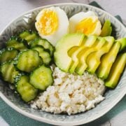 top view of breakfast bowl with cottage cheese, avocado, hard boiled egg and cucumber