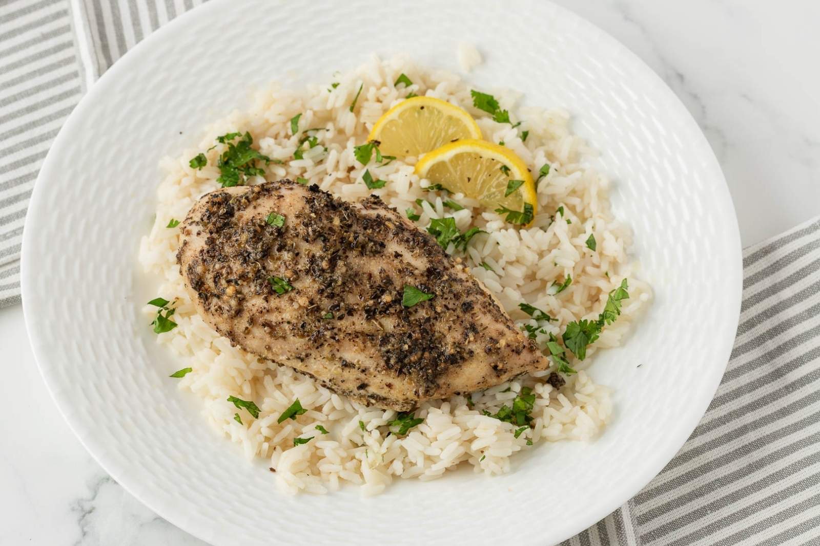 juicy baked chicken with Italian seasoning over rice on a plate