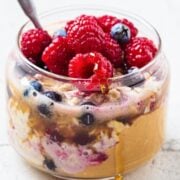 a jar with peanut butter and jelly overnight oats, topped with berries