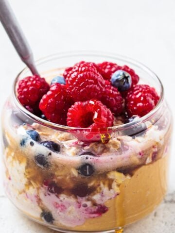 a jar with peanut butter and jelly overnight oats, topped with berries