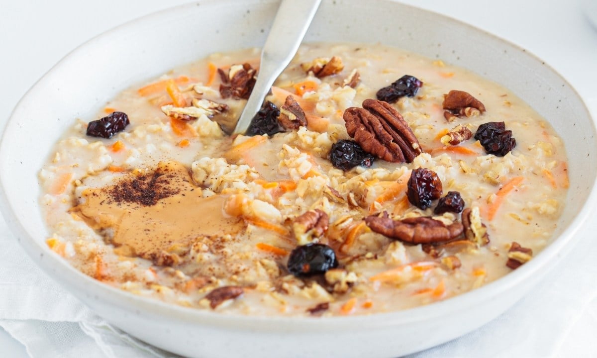 a bowl of carrot cake oatmeal topped with walnuts