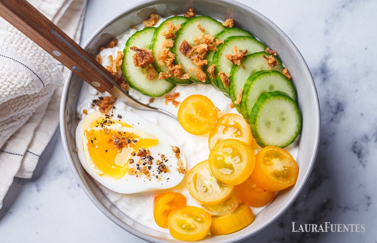 top view of a breakfast bowl with cottage cheese, cucumber, tomato, bacon and egg