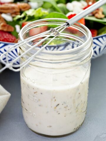 a jar of cottage cheese ranch dressing, next to a salad