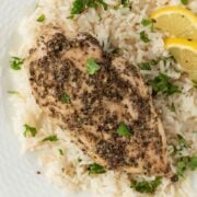 juicy baked chicken breasts with italian seasoning on top of a bed of rice