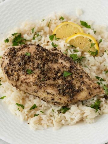 juicy baked chicken breasts with italian seasoning on top of a bed of rice
