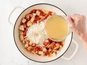 overhead view of adding chicken broth and rice to the skillet
