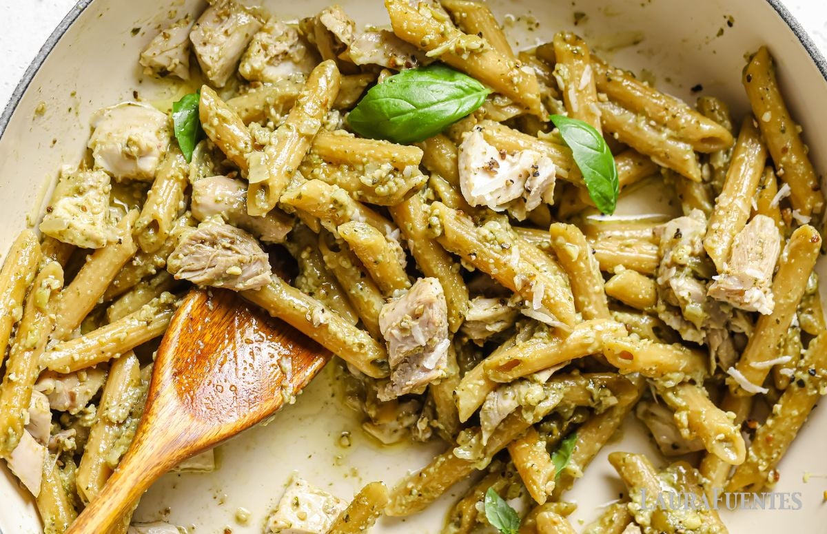 rotisserie chicken pesto pasta in a pan with a wooden spoon