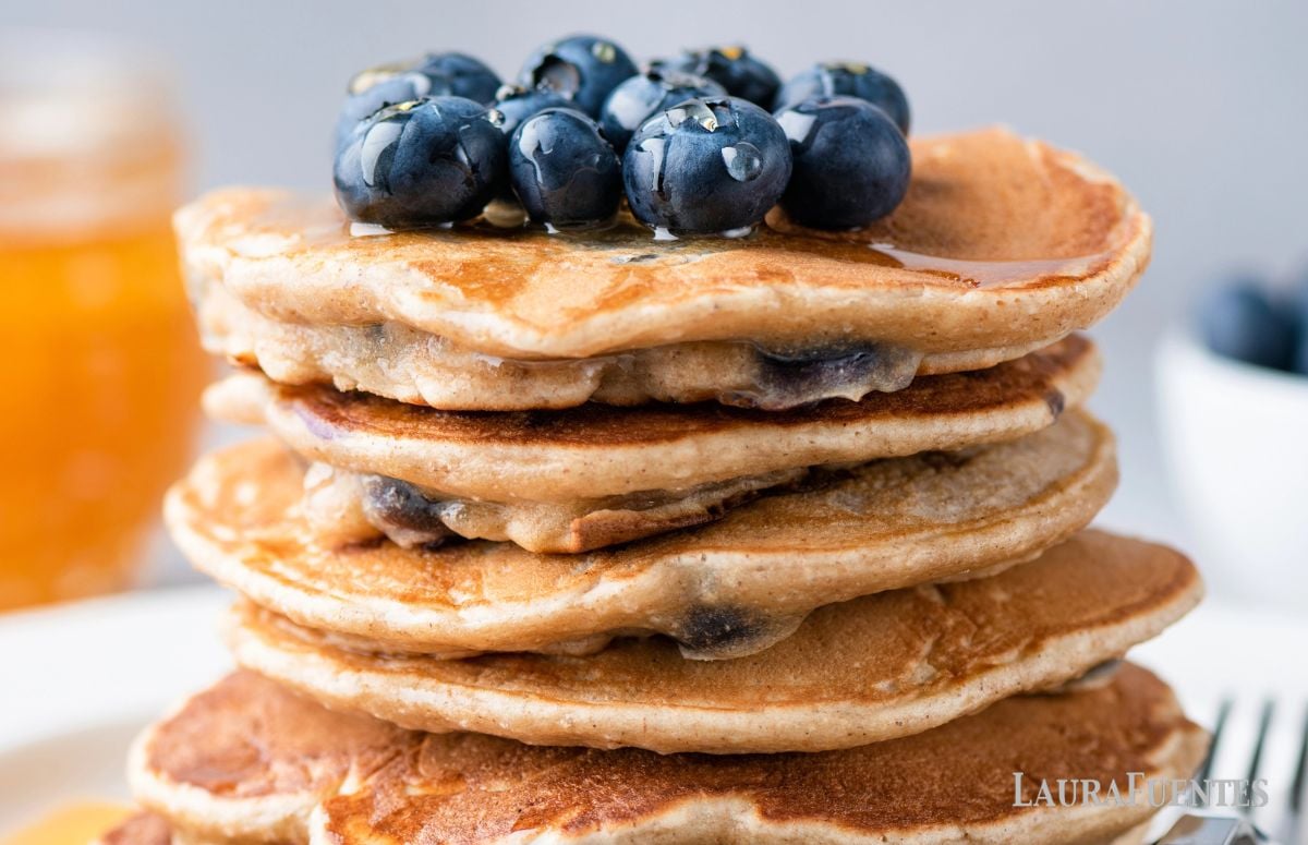 closeup of a stack of whole wheat blueberry pancakes with blueberries on top
