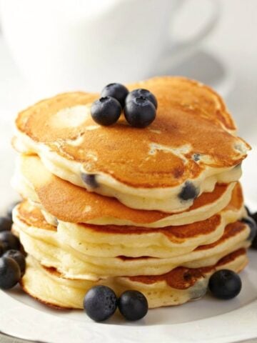 tall stack of blueberry buttermilk pancakes topped with blueberries