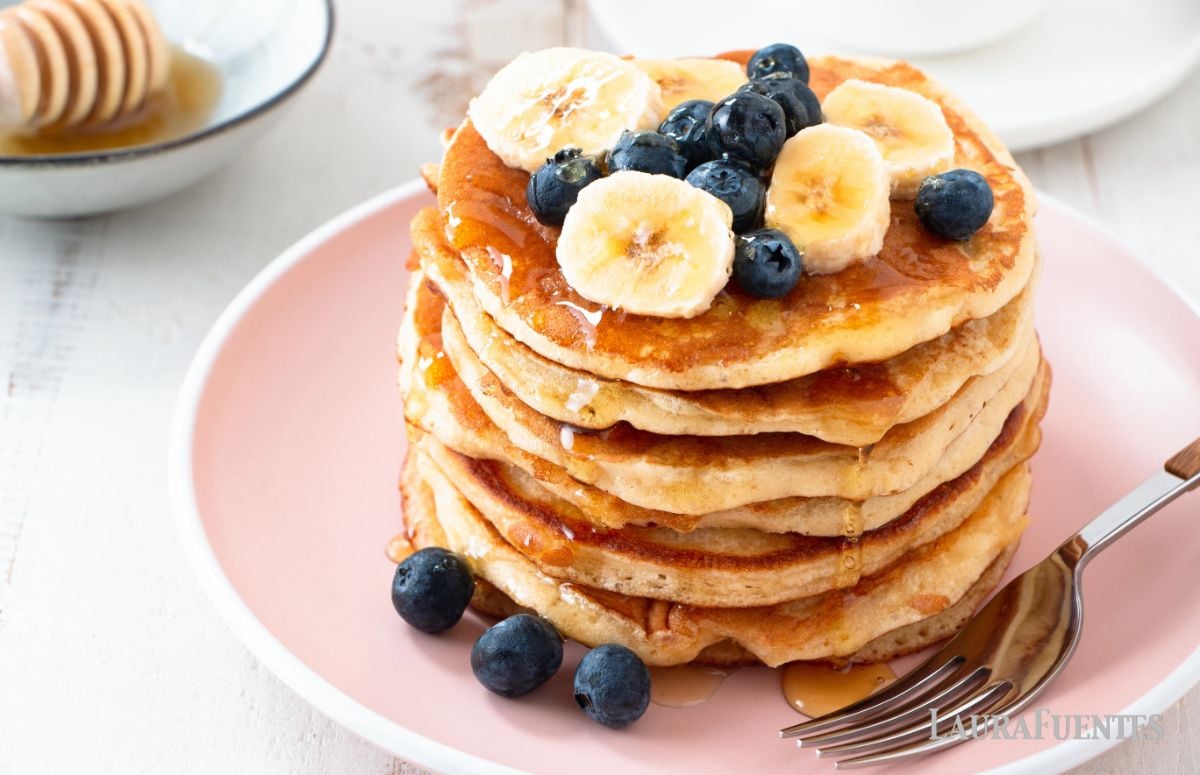 almond milk pancakes on a pink plate topped with blueberries and banana slices