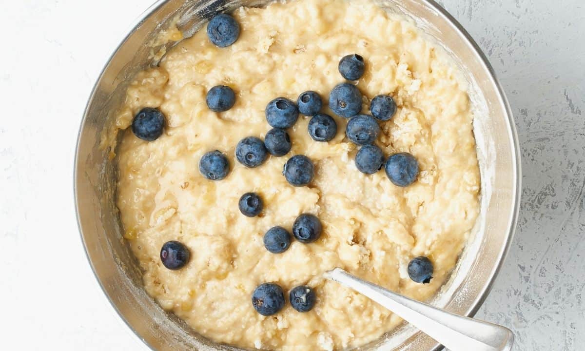 banana bread batter in a bowl with blueberries on top